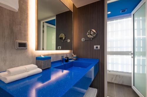 a bathroom with a blue sink and a mirror at Maitria Hotel Rama 9 Bangkok - A Chatrium Collection in Bangkok