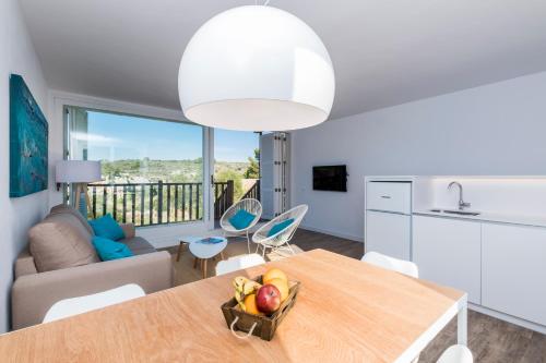 a kitchen and living room with a table with a bowl of fruit at Apartamentos Playa Canutells in Mahón