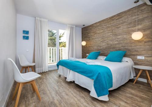 a bedroom with a large bed with blue pillows at Apartamentos Playa Canutells in Mahón