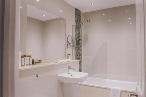 a white bathroom with a sink and a shower at Boringdon Hall Hotel and Spa in Plymouth