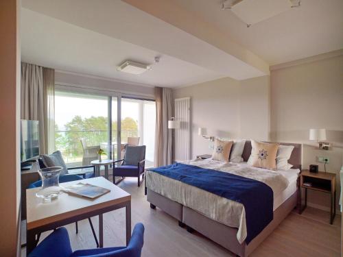 ein Hotelzimmer mit einem Bett, einem Schreibtisch und einem Zimmer in der Unterkunft Dünenresidenz Prora - 1-Raum-Ferienwohnung mit Meerblick, 1 Schlafzimmer und Balkon NP-515 in Binz