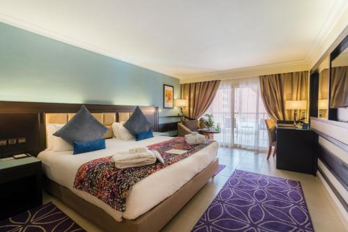 Pokój hotelowy z dużym łóżkiem z niebieskimi poduszkami w obiekcie Savoy Le Grand Hotel Marrakech w Marakeszu