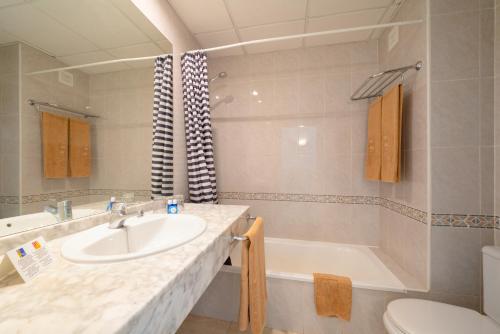 a bathroom with a sink and a tub and a toilet at Apartamentos Galeon Playa in Costa Teguise