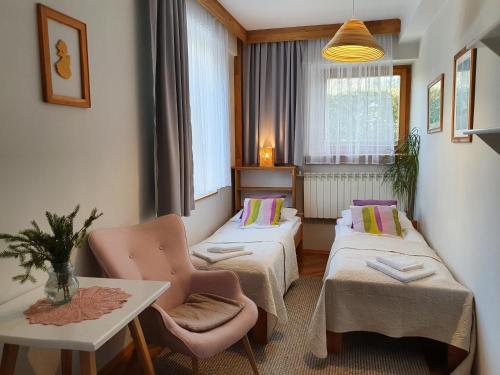 um quarto com duas camas, uma mesa e uma cadeira em Willa Iskra em Zakopane