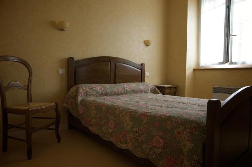 a bedroom with a bed and a chair at Hôtel Ladagnous in Peyrouse