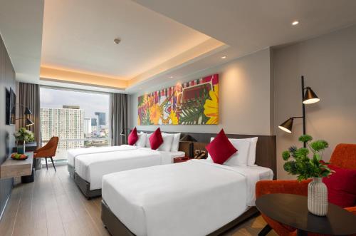 a hotel room with three beds and a table at Maitria Hotel Rama 9 Bangkok - A Chatrium Collection in Bangkok