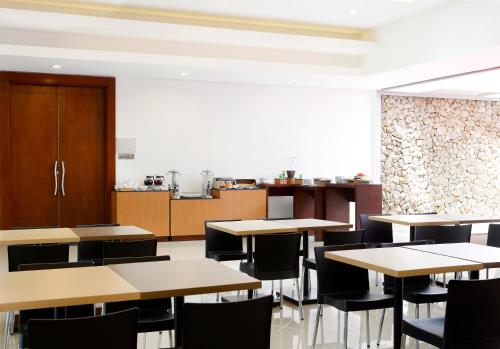 a dining room with tables and chairs and a kitchen at Amaris Hotel Muara Bungo - Jambi in Bebeko