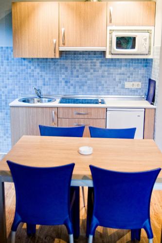 a kitchen with a wooden table and blue chairs at Posada La Robla in La Cueva