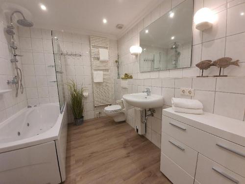 ein weißes Badezimmer mit einem Waschbecken, einer Badewanne und einem WC in der Unterkunft "Hüs Sylt" in Morsum