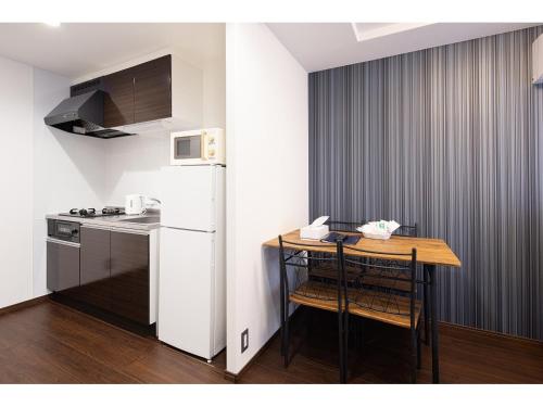 a small kitchen with a table and a white refrigerator at Coruscant Hotel NagasakiekiⅡ in Nagasaki