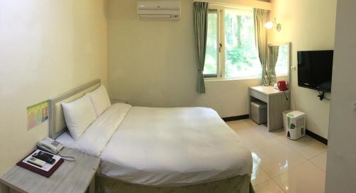 a bedroom with a large white bed and a television at Sun Moon Lake Youth Hostel in Yuchi