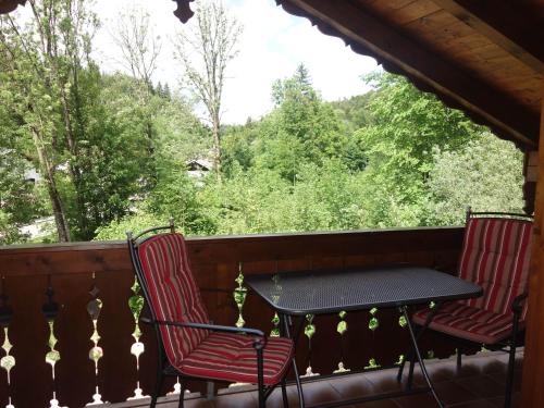 two chairs and a table on a porch with trees at Spechthäusl in Bayerisch Gmain