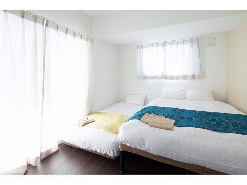 two beds in a bedroom with white walls and windows at Coruscant Hotel NagasakiekiⅡ in Nagasaki