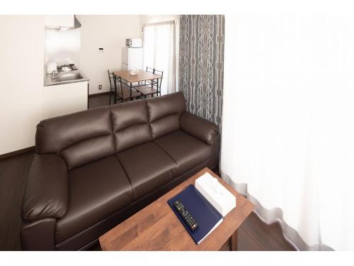 a living room with a brown couch and a table at Coruscant Hotel NagasakiekiⅡ in Nagasaki