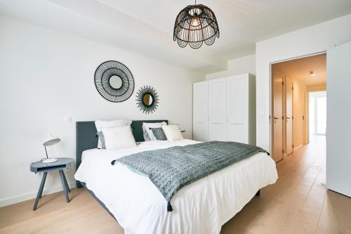 a white bedroom with a large bed and a mirror at Diamant 2BR in Brussels
