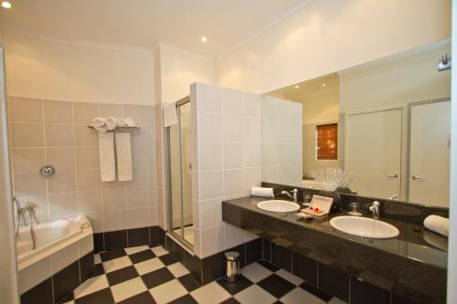 a bathroom with two sinks and a tub and a mirror at Hlangana Lodge in Oudtshoorn