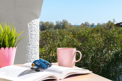 a cup and a book on a table with a pen and a mug at House of Paradise in front of the golf court-sea in Rhodes Town