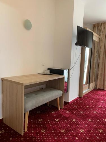 a room with a desk and a television on a red carpet at Hotel Veștem in Veştem