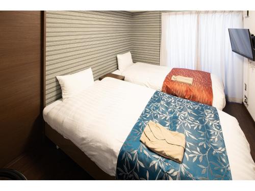 a hotel room with two beds and a television at Coruscant Hotel NagasakiekiⅡ in Nagasaki