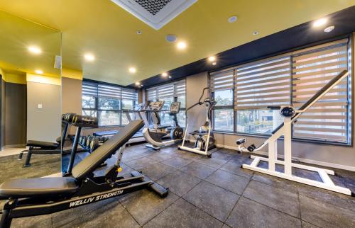 a gym with treadmills and ellipticals in a room with windows at Ventimo Hotel & Residence Jeju in Jeju