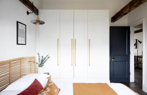 een slaapkamer met witte kasten en een blauwe deur bij Cosy Loft Apartment - minutes from Angel Tube St. in Londen