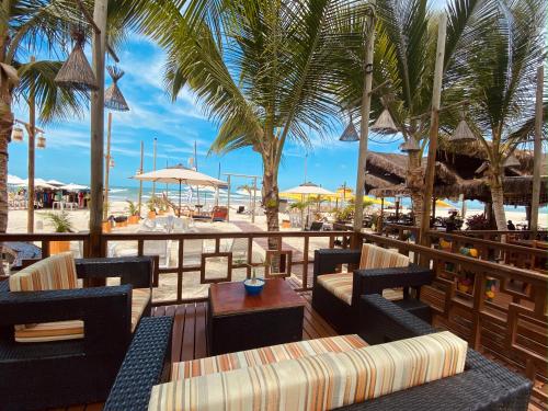 um pátio de resort com cadeiras, mesas e palmeiras em Pousada Janelas do Mar em Flecheiras