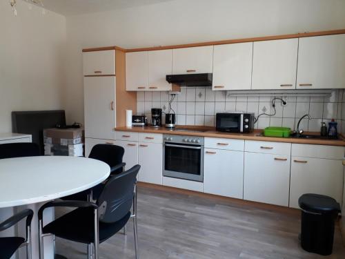 Una cocina con gabinetes blancos y una mesa y sillas. en Monteurhaus Scheidter 42, en Saarbrücken