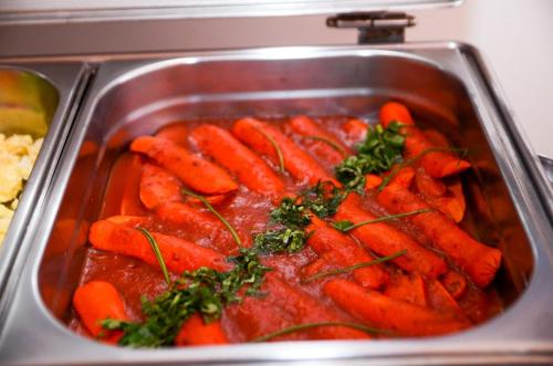 a tray of carrots with sauce in a pan at Hotel Canaã Express in Jarinu
