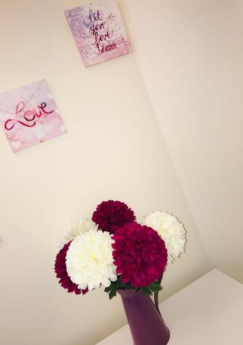 a purple vase with purple and white flowers on a table at Pavilion Holiday Apartments in Weston-super-Mare