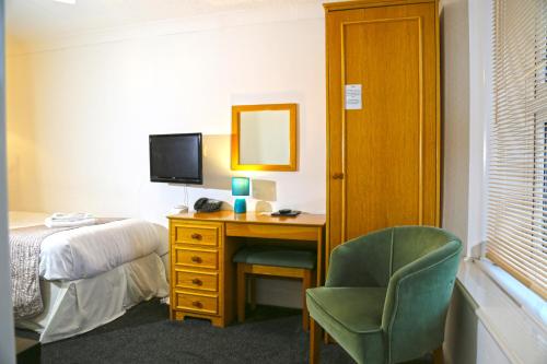 a bedroom with a desk and a bed and a chair at Westberry Hotel in Bodmin