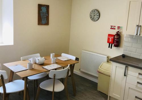 a kitchen with a table with chairs and a clock on the wall at Pavilion Holiday Apartments in Weston-super-Mare