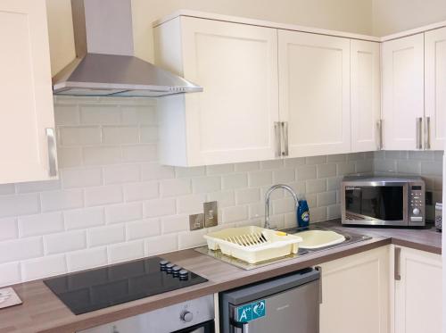 a kitchen with white cabinets and a sink at Pavilion Holiday Apartments in Weston-super-Mare