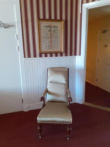 a chair in a hallway with a picture on the wall at Hotell S:t Olof in Falköping