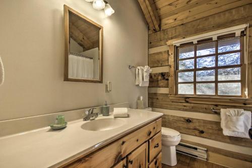 a bathroom with a sink and a toilet and a mirror at Riversong Luxe Cabin with Fire Pit on North River in Slanesville