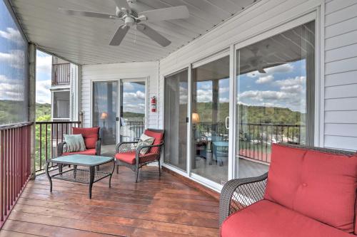 a screened porch with red chairs and a table at The Lake Escape with Balcony and Pool Access! in Camdenton