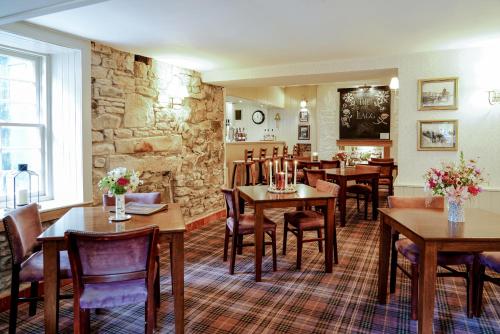 a restaurant with tables and chairs and a stone wall at The Lagg in Lagg