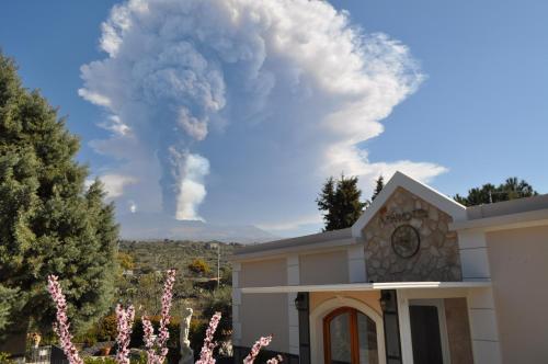 a smoke stack behind a house with pink flowers at Agri Art Croce Vallone in Biancavilla