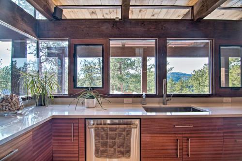 een keuken met houten kasten, een wastafel en ramen bij Chic Boulder Mountain Home with Hot Tub and Views in Boulder