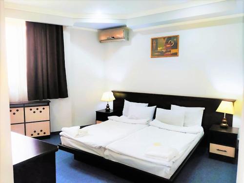 - une chambre avec un lit doté de draps et d'oreillers blancs dans l'établissement DDD Hotel, à Erevan