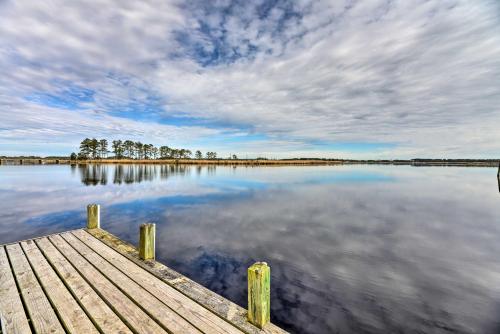 a dock on a lake with a cloudy sky at Waterside Belhaven House and Cottage with Porch and Dock in Belhaven