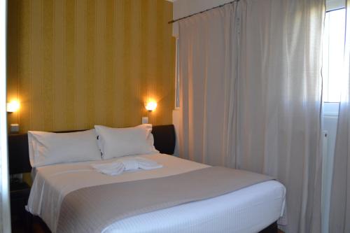 a bedroom with a white bed with two towels on it at Rivitel Marousi Apartments in Athens