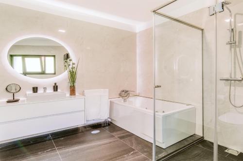 a bathroom with a tub and a sink and a mirror at Villa Belmonte by LovelyStay in Ponta do Sol