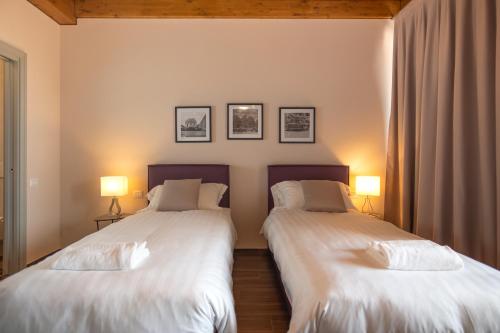 two beds in a room with two lamps at Borgo di Drugolo in Lonato del Garda