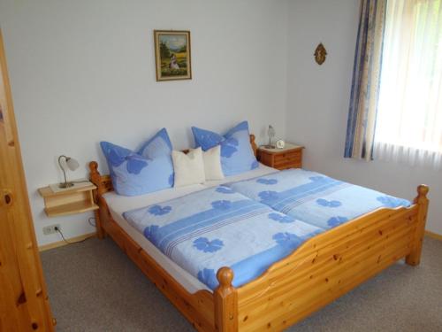 sypialnia z drewnianym łóżkiem z niebieskimi poduszkami w obiekcie Haus Elisabeth w mieście Unterwössen
