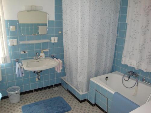 een blauw betegelde badkamer met een bad en een wastafel bij Haus Elisabeth in Unterwössen