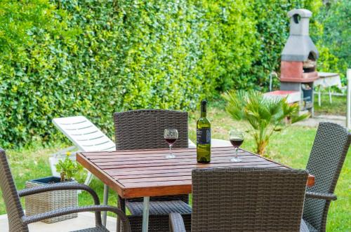 a bottle of wine sitting on a wooden table with two glasses at Color Apartments in Mlini