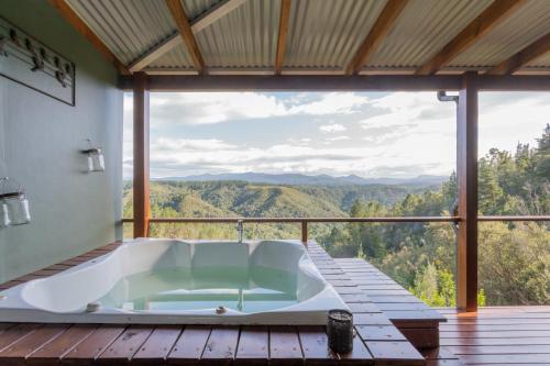a bath tub on a deck with a view of the mountains at Forest Valley Cottages in Knysna