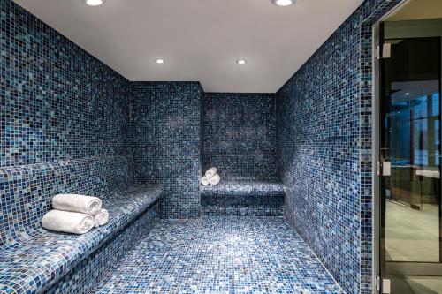 GoderdziにあるAmbassadori Goderdzi Hotelの青いタイル張りのバスルーム(タオル付きのバスタブ付)
