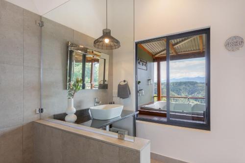 a bathroom with a tub and a sink and a window at Forest Valley Cottages in Knysna