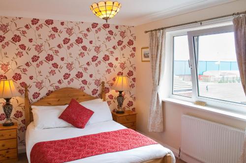 a bedroom with a bed with a red blanket and a window at The Seacliffe - Whitby in Whitby